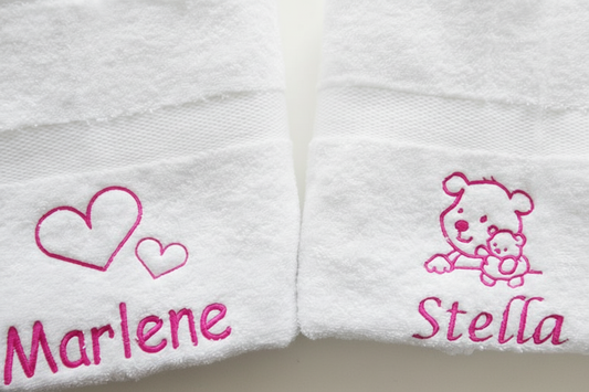 Handdoek met naam geborduurd – twee witte handdoeken met roze borduursel, namen en afbeeldingen